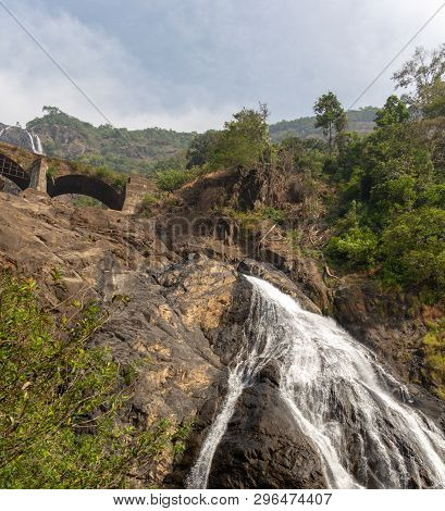 Railway Bridge Over The River Mandovi On The Background Of The Dudhsagar Waterfall