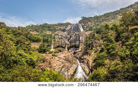 Railway Bridge Over The River Mandovi On The Background Of The Dudhsagar Waterfall
