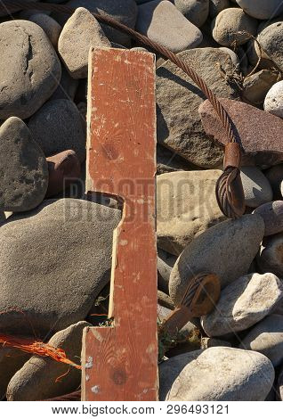 Distressed Wood Plank And Metal Cable Rubbish On Rocky Beach Front In Strong Sunlight