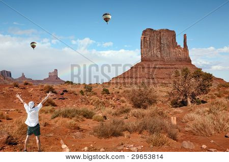 Enthusiastic tourists in Monument Valley. Famous red sandstone monoliths, fly over them colorful balloons