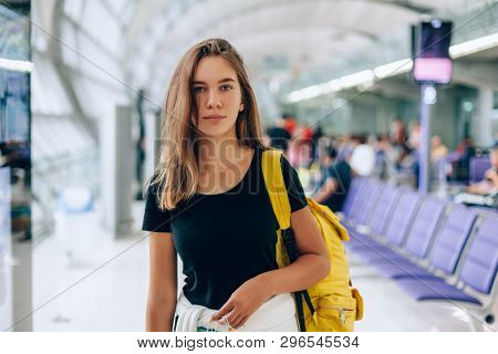 Teen girl waiting for international flight in airport departure terminal. Young passenger with backpack travelling on airplane. Teenager tourizm abroad alone concept.