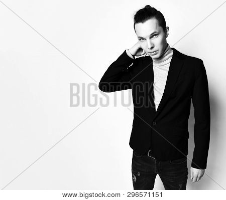 Tall Stylish Man With A Modern Bun On Head In Black Jacket And Worn Jeans Adjusts Collar Of His Grey