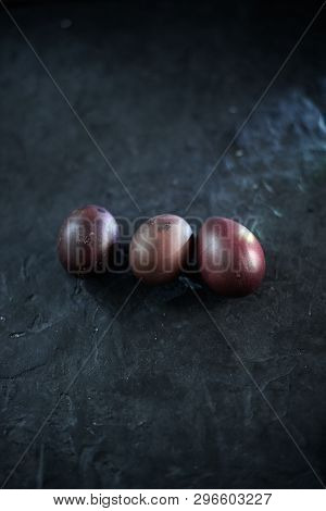 Dark Purple Eggs On A Rough Cement Background.