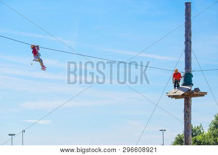 Little Brave Caucasian Girl Using A Zip Line. An Indefinited Man Lend A Helping Hand.