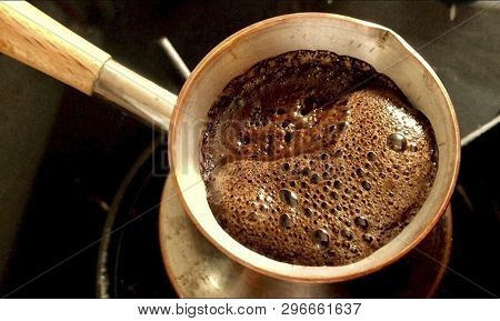 Barista Preparing Hot Tasty Drink From Copper Turk, Boils Water For Coffee On Small Fire In Cezve. C