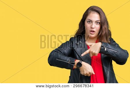 Beautiful plus size young woman wearing a fashion leather jacket over isolated background In hurry pointing to watch time, impatience, upset and angry for deadline delay