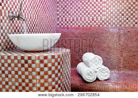 Traditional Turkish Hamam With Stone Walls, Sink And Stack Of  Clean Towels