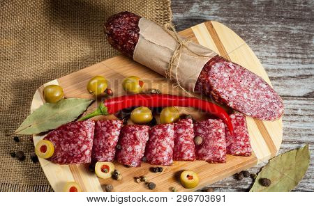 Italian Salami With Olives And Spices On Wooden Background