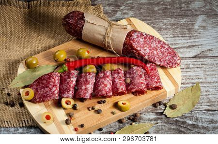 Italian Salami With Olives And Spices On Wooden Background