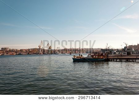 Sebastopol, Russia - November 4, 2018: Port View With Cranes And Fishermen Fishing On A Boat