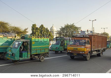 Delhi India - 09.02.2019 Indian Moto Trucks In City Traffic On A Background Of Green Trees And The D