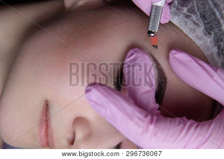 Permanent Makeup For Eyebrows. Microblading Brow. Beautician Doing Eyebrow Tattooing For Female Face