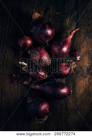 Few red whole onions stored in a grunge wooden crate or box. Shallots- a most common cooking ingredient shot from above. A rustic food still life photography.