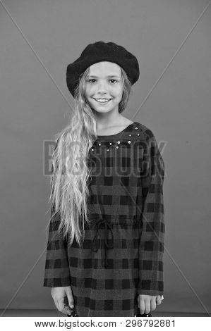 Kid Little Cute Girl With Long Hair Posing In Hat Red Background. Fashionable Beret Accessory For Fe