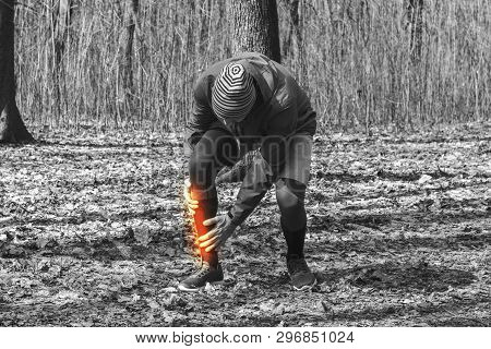 A Man In Training Clothes Injured The Periosteum While Jogging In Outdoor Workout. Concept Of Sports