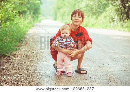 The Child Learns To Walk In The Park Barefoot On The Grass