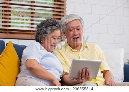 Happy Asian Senior Couple Use Tablet Video Chatting To Family At Home.aging At Home Concept