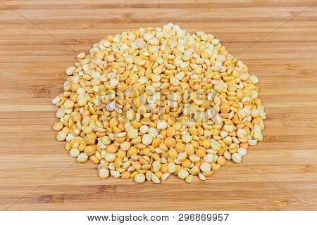 Small Pile Of Raw Yellow Variety Of The Split Peas On A Bamboo Wooden Surface
