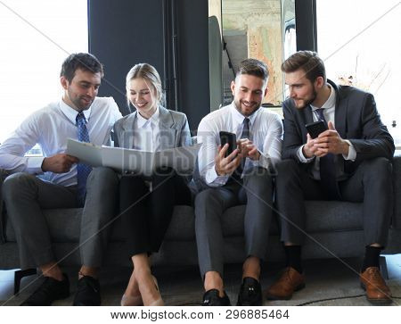 Group Of Four Business People Sitting On Sofa. They Couldnt Be Happier About Working Together.
