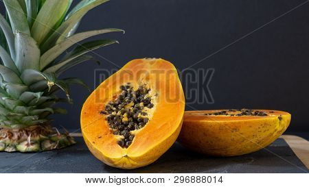The Papaya Is Cut Into Two Halves, The Stand Is A Stone Board With A Wooden Frame, Near The Papay Th