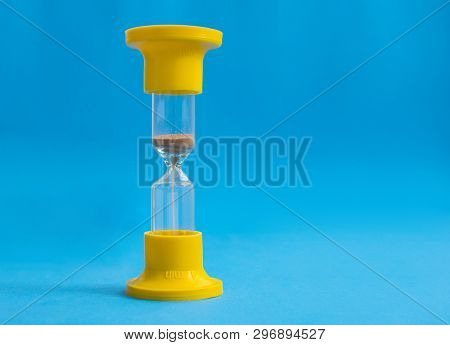 Yellow Hourglass On Blue Background. Time And Glass.