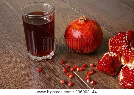 Stil Life - Red Whole And Cutted Pomegranate Fruits, Scattered Seeds And Glass With Juice On A Dark 