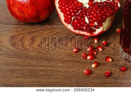 Stil Life - Red Whole And Cutted Pomegranate Fruits, Scattered Seeds And Glass With Juice On A Dark 