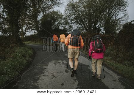 Sarria, Spain - April 7th, 2019: Camino De Santiago Pilgrims Walking With A Backpack Across A Rural 