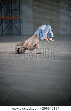 An Athletic Man On Capoeira Training. Standing On One Hands In An Unnatural Pose