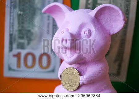 Pink Pig Holding Hryvna Coin. Pig With Hryvna Coin Against The Background Us Dollars Background. Uah