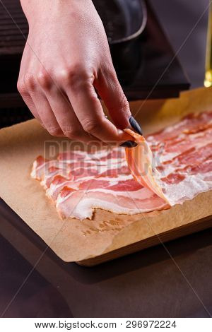 Young Woman In A Gray Apron Fries Bacon