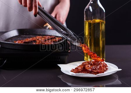 Young Woman In A Gray Apron Fries Bacon