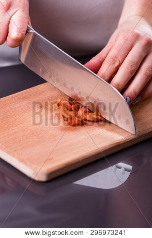 Young Woman In A Gray Apron Cuts Roasted Bacon