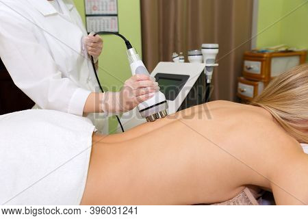The Spa Beautician Holds The Rf-lifting Maniple In His Hand And Runs It Along The Clients Back.