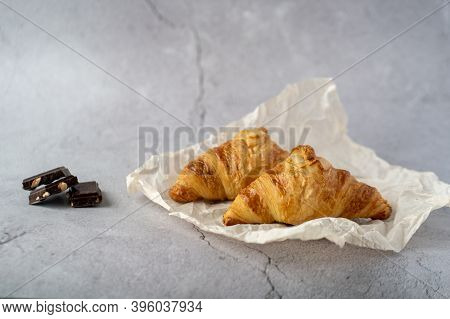 On A Gray Table Two Croissants Lie On A Gray Background Next To Three Pieces Of Chocolate