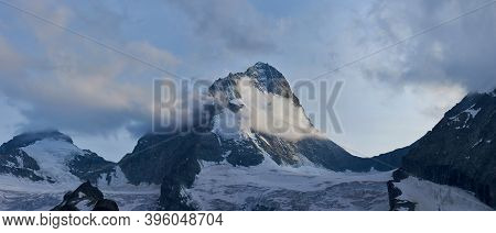 Panoramic Snapshot Of Dent Blanche In Swiss Alps, Slightly Covered In Clouds, Much Snow At The Foot
