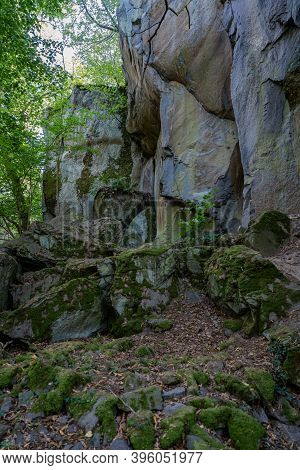 Rocks At The Foot Of A Steep Wall In The Forest.