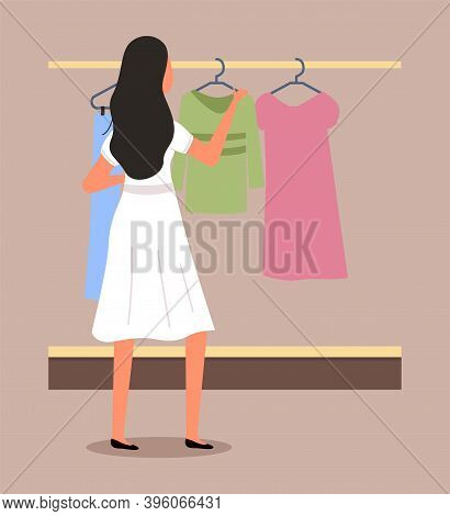 Girl Chooses Clothes On The Hanger On Shopping. Female Buyer Is Selecting Clothes In A Store. Young 
