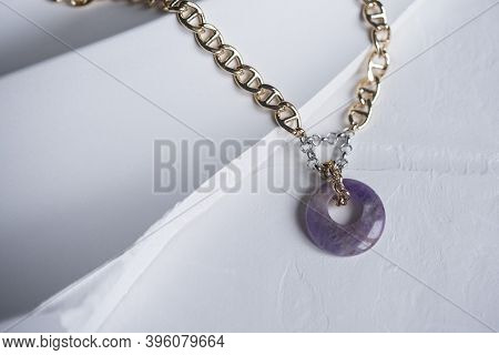 Gold Chain Jewelry And Charoite Ring Pendant On A Textured Plaster Board. Jewelry, Necklace, Holiday