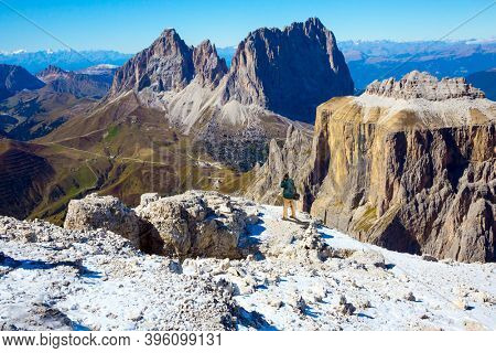 Tourist with photo bag taking pictures of scenic landscape. The Pordoi Pass is part of the Dolomiti Superski ski resort. Dolomites in the snow. Alps of South Tyrol. Italy. 