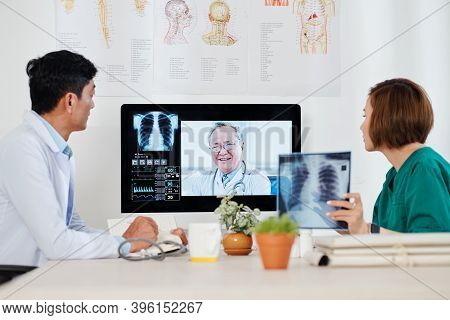 Group Of Aisan Pulmonologists Discussing Chest X-rays And New Ways Of Pneumonia Treatment