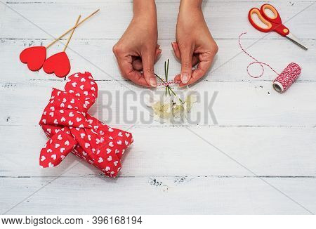Womens Hands Wrappes Gift For Valentines Day, Birthday, Mothers Day Using Red Textile And Flowers On
