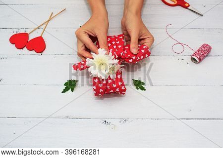 Womens Hands Wrappes Gift For Valentines Day, Birthday, Mothers Day Using Red Textile And Flowers On