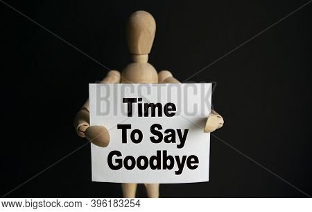 The Wooden Man Holds A White Sign With The Text Time To Say Goodbye In His Hands. The Content Of The