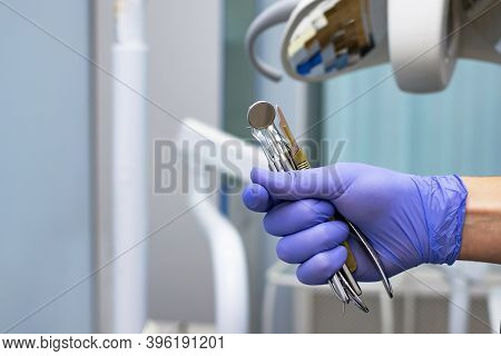 Close-up Of A Dentist Mirror, Tools In The Hands Of A Dentist On The Background Of A Medical Office.