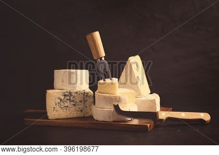 Different Types Of Cheese, Knife And Fork On Black Table