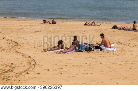 CASCAIS, PORTUGAL - SEPTEMBER 19, 2020: People sunbathing on the Praia da Rainha beach in Cascais, Portugal. Cascais is famous and popular summer vacation spot for Portuguese and foreign tourists
