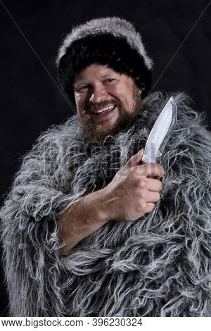 Bearded Hunter Dressed In A Fur Mantle And Fur Hat With Knife