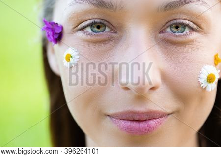 Young Fresh Womans Face With Wild Flowers And Daisy. Woman Eyes With Natural Make-up. Natural Cosmet