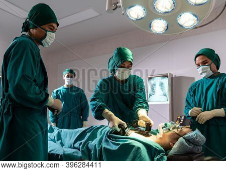 Surgeon doctor and nurse using Defibrillator to patient while patient have problem with Sudden Cardiac Arrest while surgery in Operating Room OR. Medical health care Surgery concept.